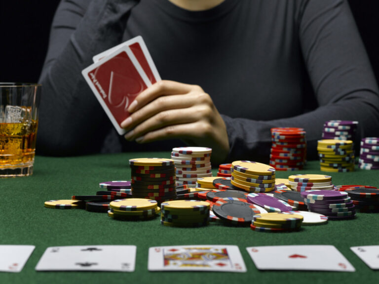 Young woman holding cards at poker table, mid section